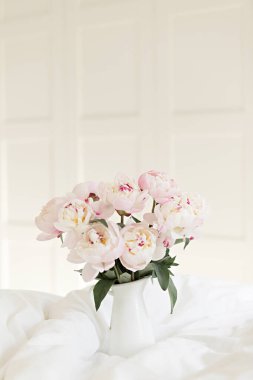 Beyaz çarşaf üzerinde pembe şakayık demeti. Yatak odasında modern bir iç mekan. Düğün ve festival tarzı.