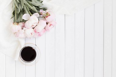 Pembe laleli stil kompozisyonu ve ahşap arka planda fincan kahvesi. Çiçek çerçevesi ve beyaz tekstil yatıyordu. Kenarlık üst görünümü.