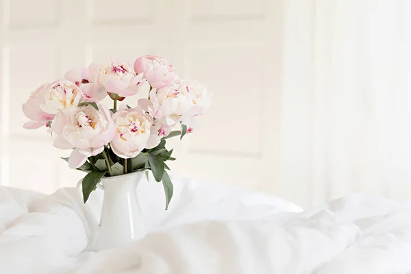 Strauß rosa Pfingstrosen auf weißer Bettwäsche. Moderne Einrichtung im Schlafzimmer. Hochzeit und festlicher Stil. — Stockfoto