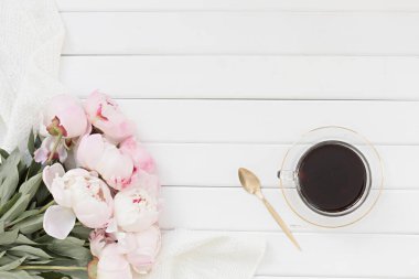 Pembe laleli stil kompozisyonu ve ahşap arka planda fincan kahvesi. Çiçek çerçevesi ve beyaz tekstil yatıyordu. Kenarlık üst görünümü.