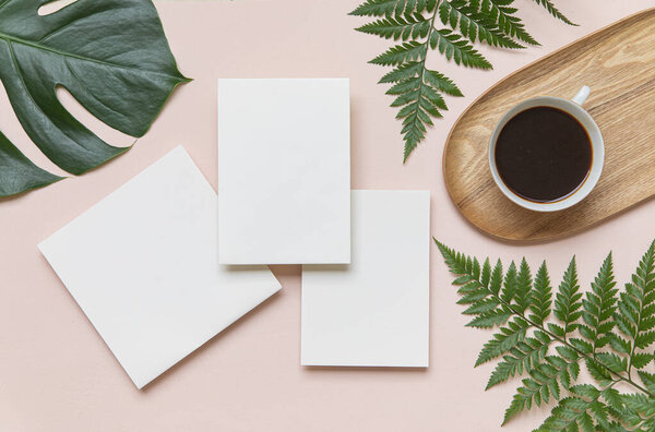 Styled summer wedding mockup. Blank greeting and invitation card. Green tropical leaves with invitation card on table.