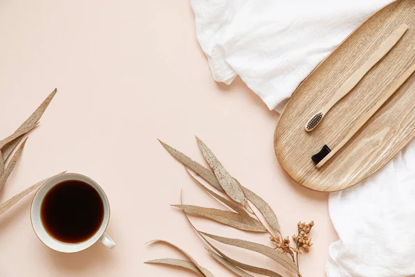 Brosse à dents en bambou et café sur une table avec espace de copie sur un fond rose. Composition stylisée de la couche plate avec des feuilles d'eucalyptus séchées. — Photo