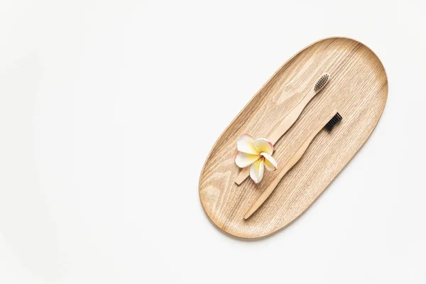 Escova de dentes de bambu em uma mesa com espaço de cópia em um fundo branco. Composição estilizada de flat lay com flores tropicais. — Fotografia de Stock