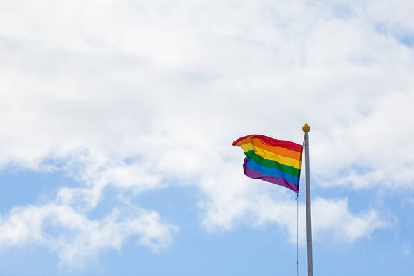 Flag with a rainbow on a blue sky background. lgbt concept.