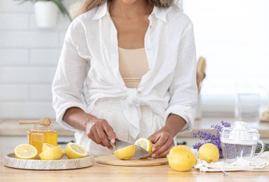 Taze lavantalı limonata. Üçüncü adım, yaz kokteyli yapmak için gerekli malzemeler. Kullanıcı rehberi. Kız bir içki hazırlıyor ve mutfakta limon kesiyor..