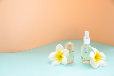 Beyaz arka planda bir şişe önemli yağ ve tropikal çiçek. Deri ve vücut bakımı kavramı.