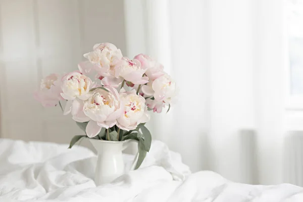 Bouquet of pink peonies on white bed linen. Modern interior in the bedroom. Wedding and festive style. — Stock Photo, Image