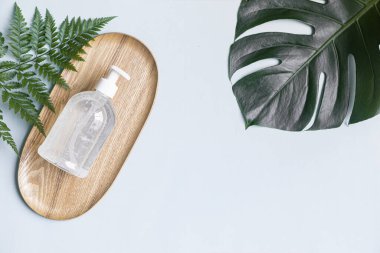 Beyaz şişe ve tropik arka planda palmiye yapraklarıyla cilt bakımı kavramı.