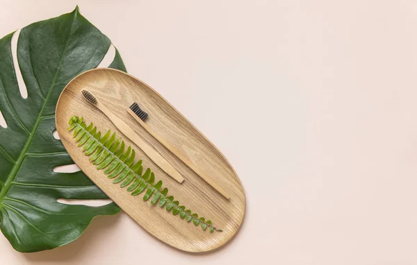 Cepillo de dientes de bambú en una mesa con espacio para copiar sobre un fondo rosa. Composición de estilo de la puesta plana con hojas tropicales. — Foto de Stock