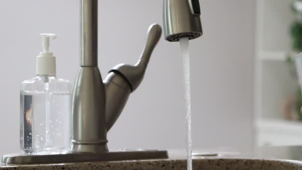 Les hommes versent de l'eau dans le verre du robinet chromé pour boire de l'eau courante avec des bulles d'air. Désinfectant pour les mains est à proximité, pendant le virus de la couronne ne recommande pas de boire de l'eau brute. 4k — Video