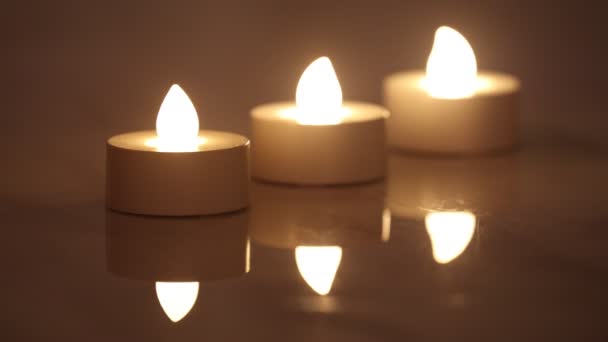 Три горящих е-свечи в линии с отражением в темном фоне — стоковое видео