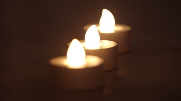 Drei brennende E-Kerzen in einer Reihe mit dunklem Hintergrund — Stockvideo