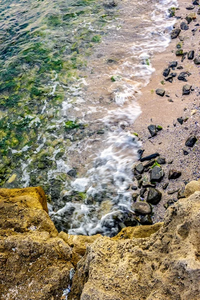 Vlny valí na skalách písečného pobřeží — Stock fotografie