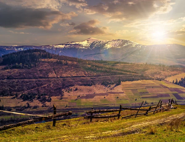 Rural area with snowy mountain tops at sunset — Stock Photo, Image
