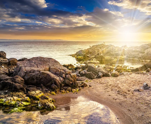 Piedras y algas en la costa rocosa del mar al atardecer —  Fotos de Stock