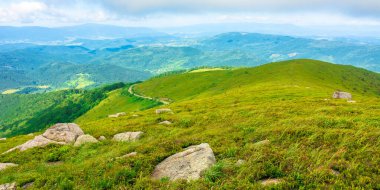 Yazın harika bir dağ manzarası. Taze yeşil ve mavi renklerde güzel bir doğa. Bulutlu bir gökyüzünün altındaki benekli ışıkta harika bir dağ manzarası.