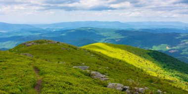 Yazın harika bir dağ manzarası. Taze yeşil ve mavi renklerde güzel bir doğa. Bulutlu bir gökyüzünün altındaki benekli ışıkta harika bir dağ manzarası.