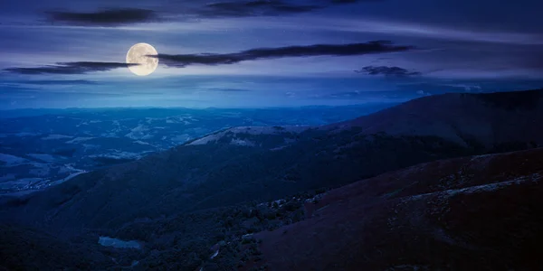 hills and meadows under the blue sky at night. hills and meadows under the blue sky at night. mountain landscape in late summer in full moon light. beautiful scenery in august