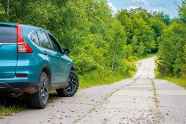 Ormandaki beton yol kenarındaki arazi aracı. kırsal seyahat konsepti. Yazın güzel doğa manzarası