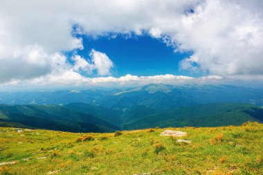 Karpatya yaz dağı manzarası. Çimen tepesinde kayalar olan güzel bir kırsal bölge. Uzaktaki vadiye bak. Mavi gökyüzündeki bulutlar. harika seyahat yeri
