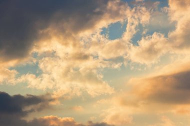 Bulutlar cennet gibi akşam ışığında. Sıcak sarı ve turuncu tonlarda doğa arkaplanı