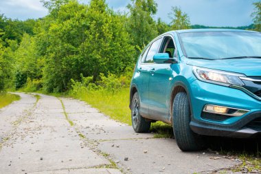 Ormandaki beton yol kenarındaki arazi aracı. kırsal seyahat konsepti. Yazın güzel doğa manzarası