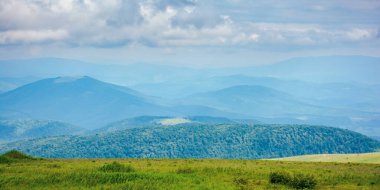 Karpat Dağları 'nın doğa manzarası. Yazın çimenli çayırları olan güzel yuvarlanan bir manzara. Gökyüzündeki bulutlar uzak havza sırtı üzerinde