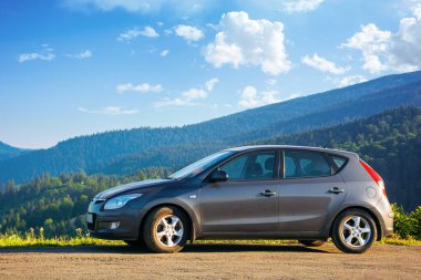 Mizhhirya, Ukrayna - 08, 2020: sabah vakti dağın tepesindeki beton parktaki araba. kırsal seyahat konsepti. Güzel doğa manzarası Yazın mavi gökyüzünde yumuşak bulutlar