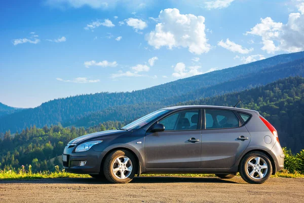 Mizhhirya, Ukrayna - 08, 2020: sabah vakti dağın tepesindeki beton parktaki araba. kırsal seyahat konsepti. Güzel doğa manzarası Yazın mavi gökyüzünde yumuşak bulutlar