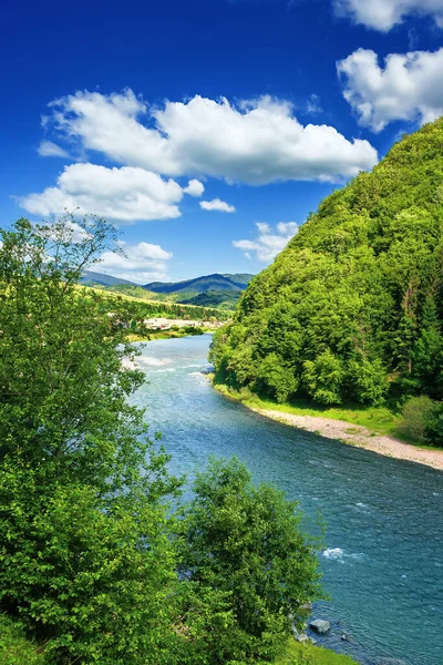 川は山の谷を流れる 美しい夏の田園風景 遠くの村だ 素晴らしい景色だ 深い青空にふわふわの雲が — ストック写真
