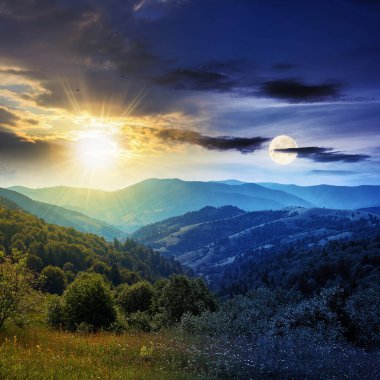 Gündüz ve gece, kırsal alanların üzerinde konsept değiştiriyor. Tepelerdeki çayırların olduğu güzel doğa manzarası Alacakaranlıkta uzak vadiye doğru yuvarlanıyor güneş ve ay ile