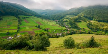 Karpat Dağları Vadisi 'ndeki köy. Sonbaharın başlarında kırsal alan. Yamaçtaki çayırlarda tarlalar ve otlaklar. Harika doğa manzarası sabahları