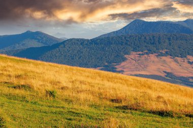 Tepelerde tarlaları olan kırsal bir yer. Yazın gün doğumunda dağlık doğa manzarası. # Uzakta parlayan bulutlar #