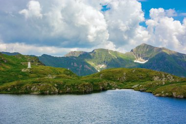 Yüksek irtifada gölü olan bir yaz manzarası. Yazın İbneler Dağı 'nın güzel manzarası. Pofuduk bulutların altındaki uzak tepeye açık görüş
