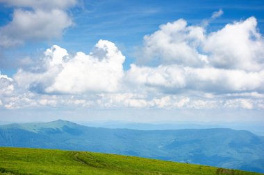 Cennet gibi yaz manzarası. Çimenli çayır ve yüksek tepe. Mavi gökyüzünde yumuşak bulutlar olan güneşli bir hava. yeşil ve mavi doğada