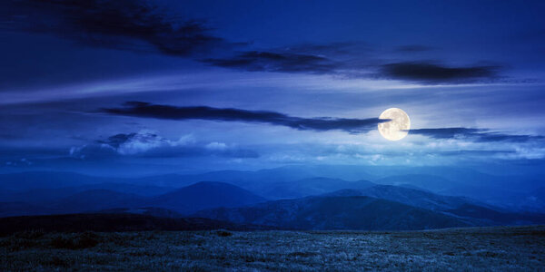 Mountain meadow at night. beautiful landscape with clouds above horizon in full moon light. wonderful nature background