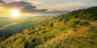 Gün batımında Karpatlar 'ın dağ manzarası. Akşamüstü yeşil yuvarlanan tepeleri olan güzel bir manzara. Yazın bulutlu dramatik bir gökyüzü altında. taşra kavramını keşfet