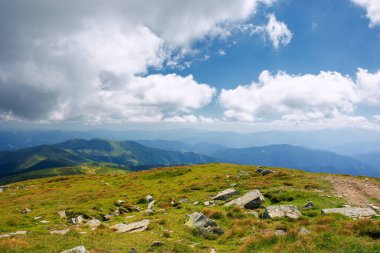 Güneşli bir günde dağ manzarası. Güzel doğa geçmişi. Çimenli çayırları olan dağlık tepenin üzerindeki bulutsu manzarası. geri dönüş ülke konsepti
