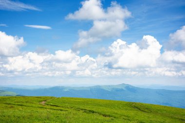 Cennet gibi yaz manzarası. Çimenli çayır ve yüksek tepe. Mavi gökyüzünde yumuşak bulutlar olan güneşli bir hava. yeşil ve mavi doğada
