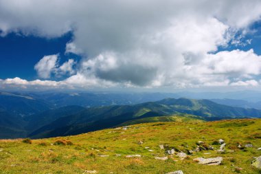 Güneşli bir günde dağ manzarası. Güzel doğa geçmişi. Çimenli çayırları olan dağlık tepenin üzerindeki bulutsu manzarası. geri dönüş ülke konsepti