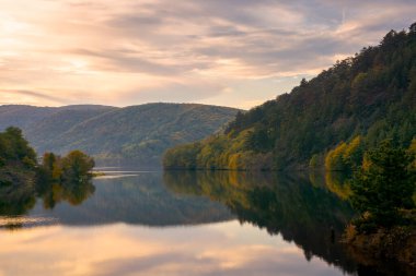 Göllü güzel bir akşam manzarası. Su yüzeyine yansıyan parlayan bulutlar. Romanya 'nın dağlarındaki muhteşem sonbahar manzarası