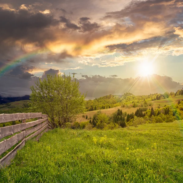 Fence on hillside meadow in mountain at sunset — Stock Photo, Image