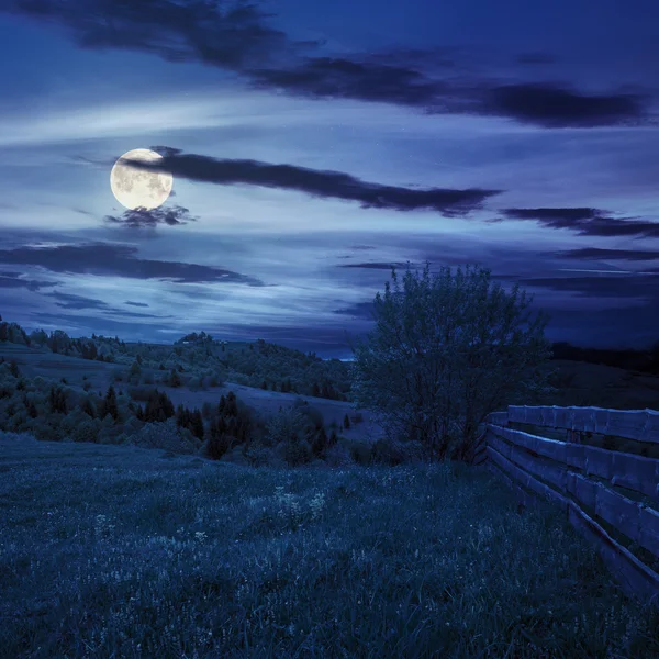 Cerca no prado encosta na montanha à noite — Fotografia de Stock