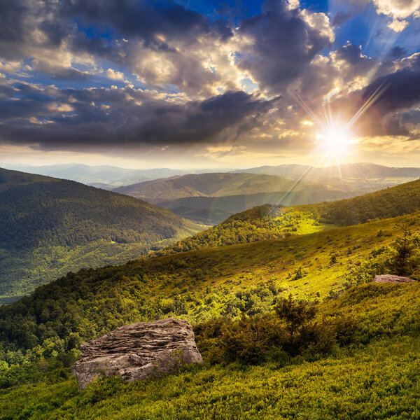 light on stone mountain slope with forest at sunset