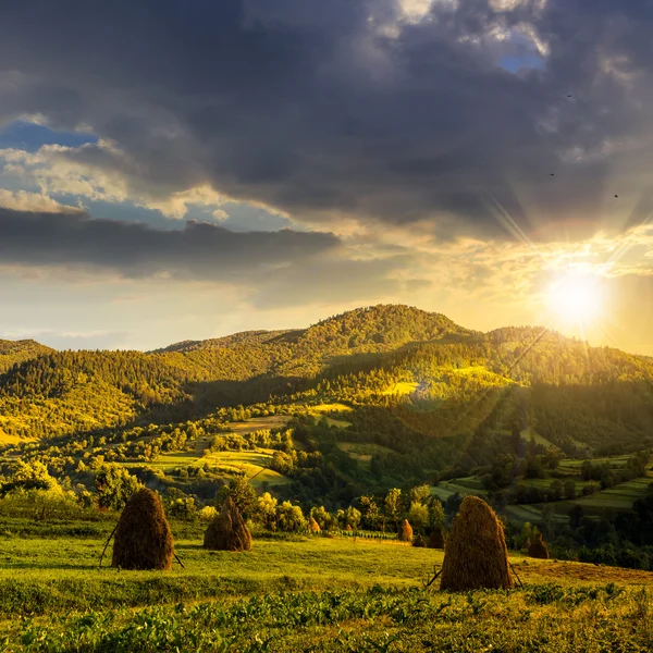 Campo con pagliaio in collina al tramonto — Foto Stock