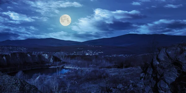 Lake in mountains quarry near city at night — Stock Photo, Image