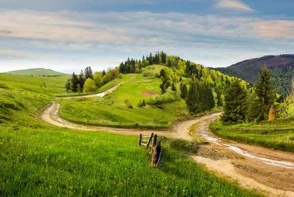 Cross road on hillside meadow in mountain at sunrise — Stock Photo, Image