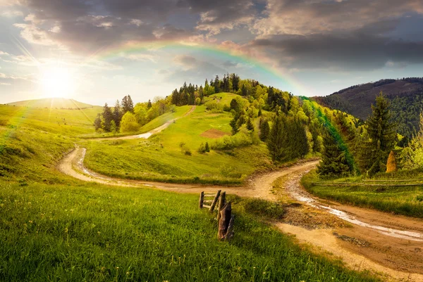 Cross road på hillside äng i berg vid solnedgången — Stockfoto