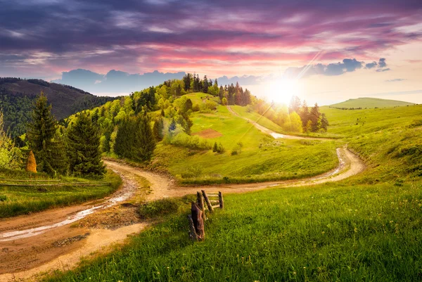Cross road on hillside meadow in mountain at sunset — Stock Photo, Image