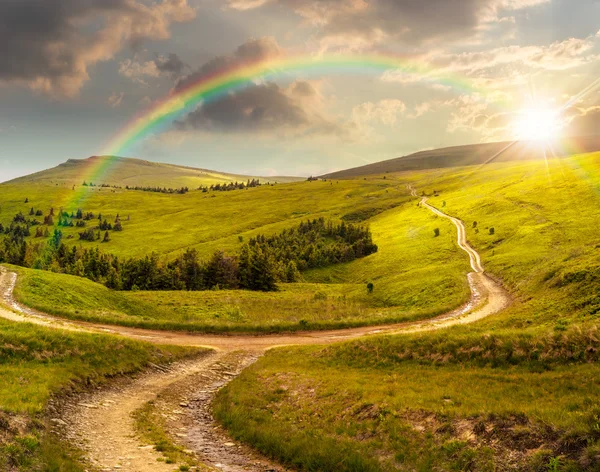 Cross road på hillside äng i berg vid soluppgången vid solnedgången — Stockfoto